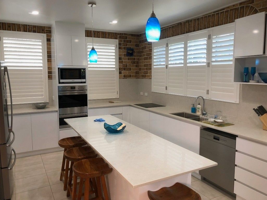 A Kitchen With White Cabinets and Stools and a Large Island — TT Shutters & Shading In Ballina, NSW