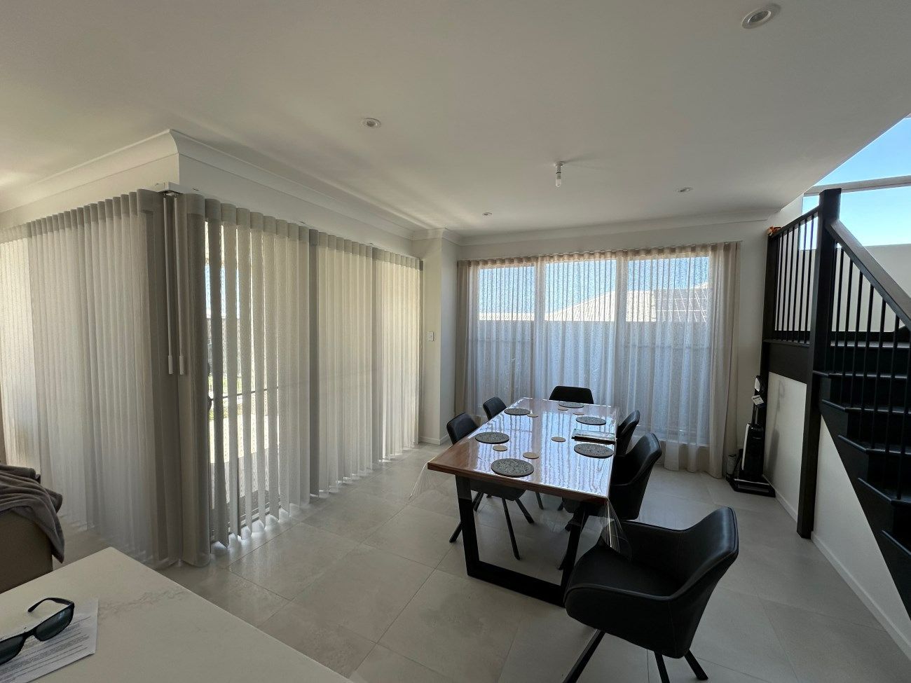 A Dining Room With a Table and Chairs and a Staircase — TT Shutters & Shading In Kingscliff, NSW