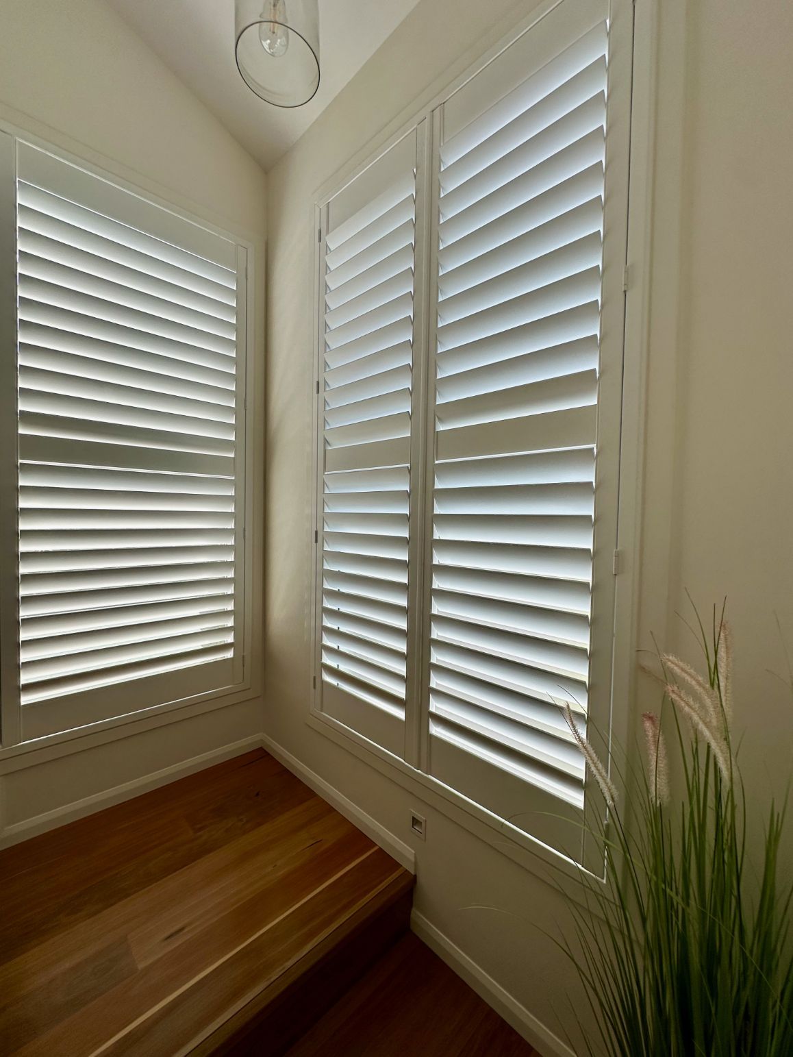 A Room With White Shutters On The Windows And A Wooden Floor — TT Shutters & Shading In Ballina, NSW