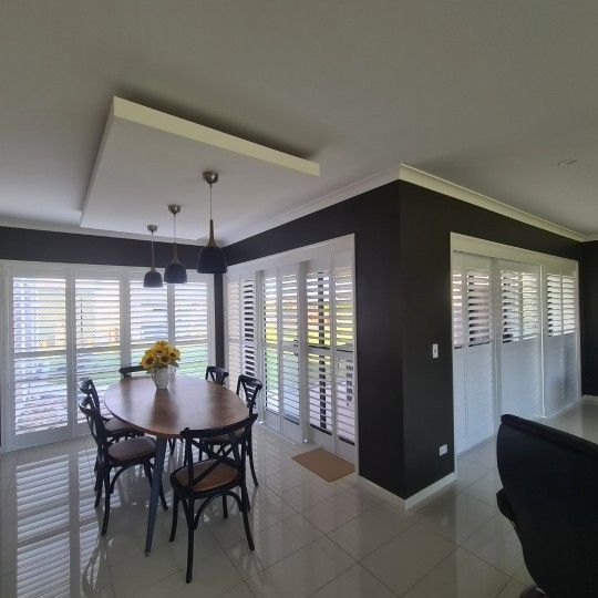 A Room With A Table And Chairs And Shutters On The Windows — TT Shutters & Shading In Ballina, NSW