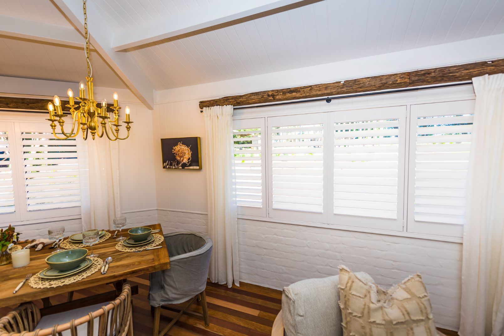 A Dining Room With A Wooden Table And Chairs And A Chandelier — TT Shutters & Shading In Ballina, NSW