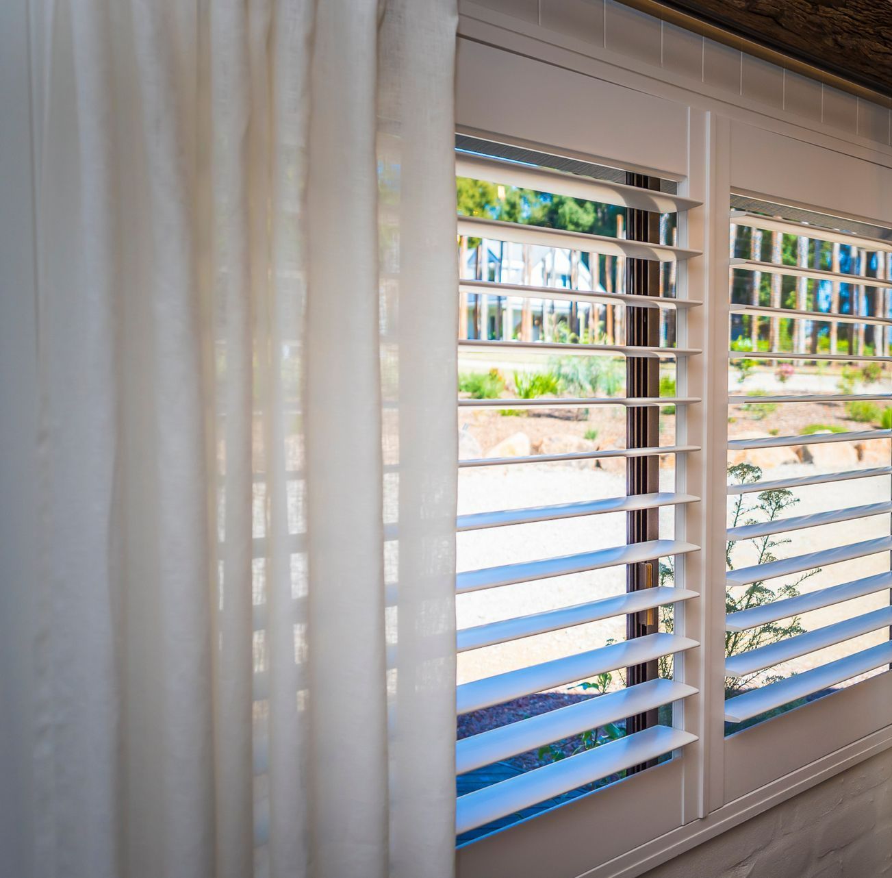 A Window With White Shutters and a White Curtain — TT Shutters & Shading In Lennox Head, NSW