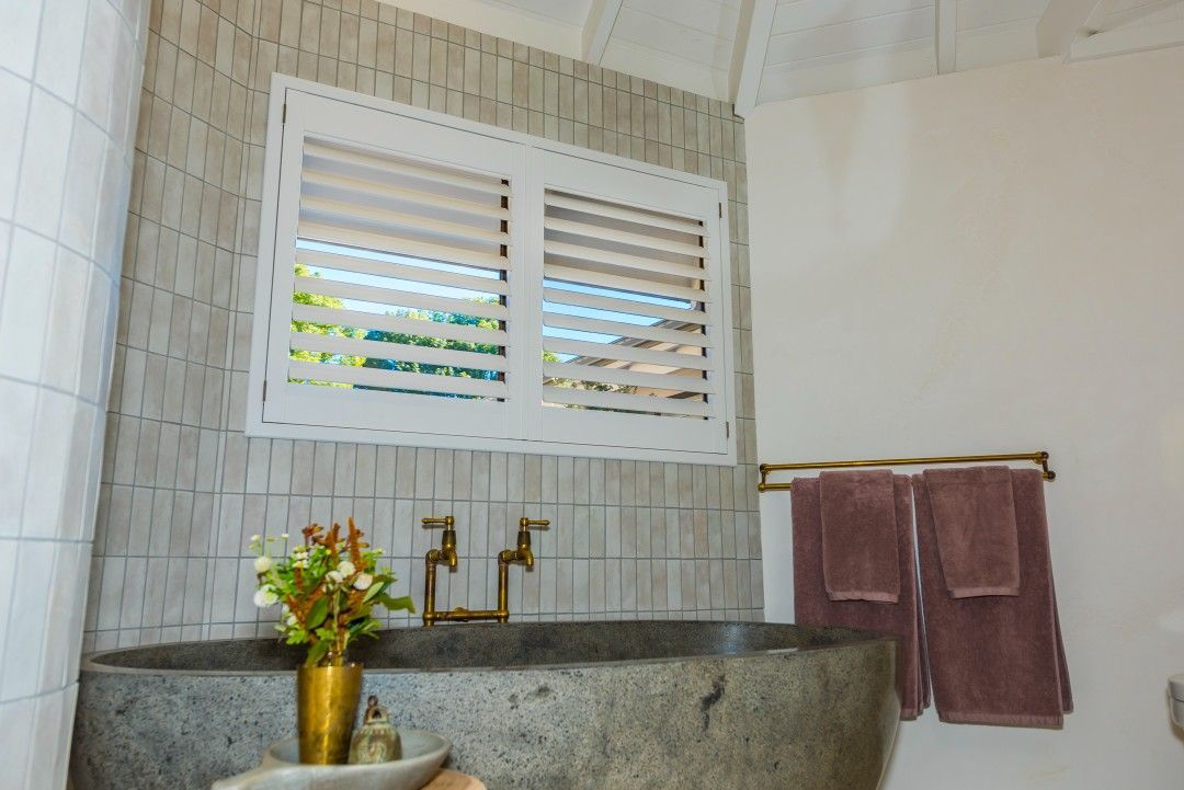 A Bathroom With A Stone Sink And A Window With Shutters — TT Shutters & Shading In Ballina, NSW