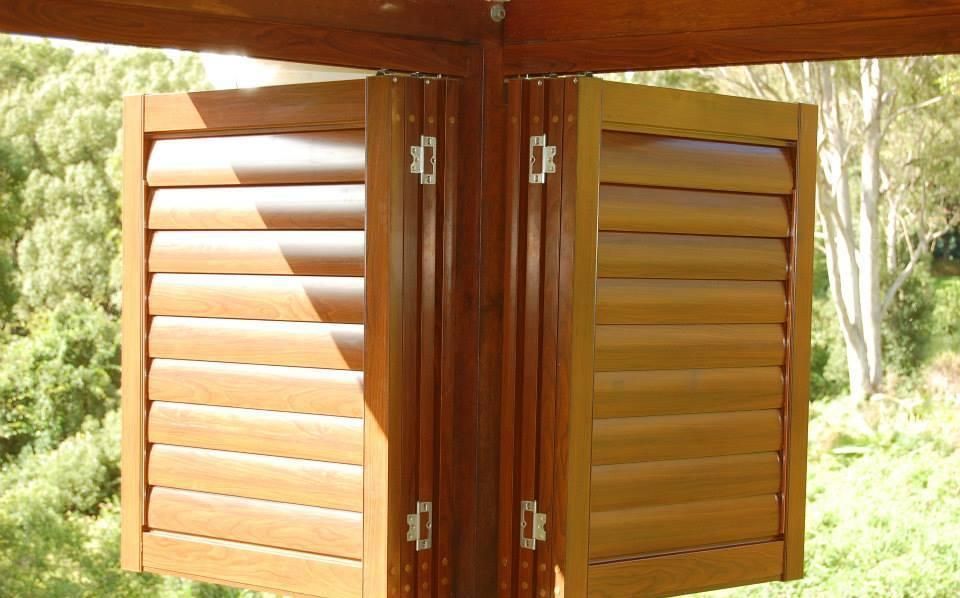 A Pair of Wooden Shutters on a Window With Trees in the Background — TT Shutters & Shading In Byron Bay, NSW