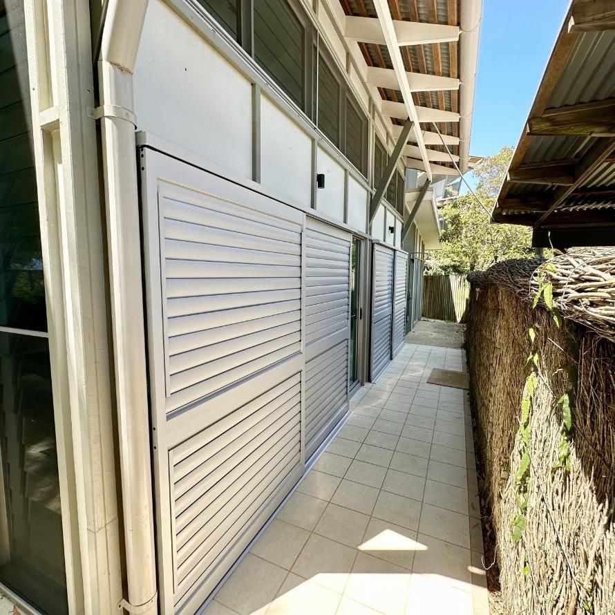A Row of White Shutters on the Side of a Building — TT Shutters & Shading In Byron Bay, NSW