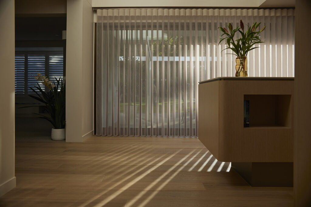 A Room With a Vase of Flowers on a Table and a Sliding Glass Door — TT Shutters & Shading In Ballina, NSW