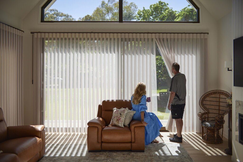 A Man is Standing Next to a Woman Sitting on a Couch in a Living Room — TT Shutters & Shading In Ballina, NSW