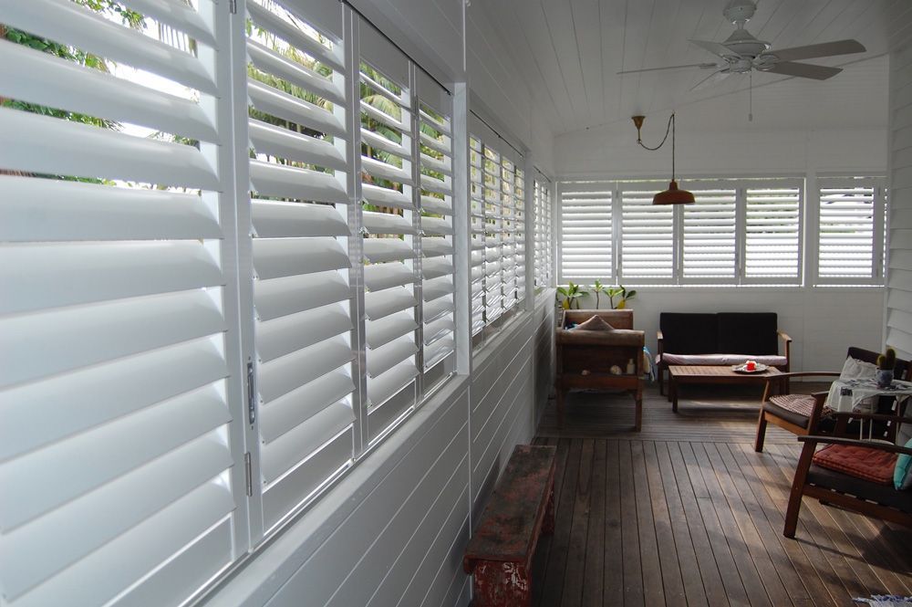 A Living Room With White Shutters on the Windows and a Ceiling Fan — TT Shutters & Shading In Lennox Head, NSW
