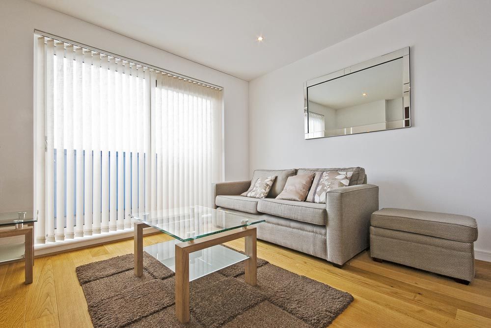 A Living Room With a Couch, Coffee Table, and Mirror — TT Shutters & Shading In Kingscliff, NSW