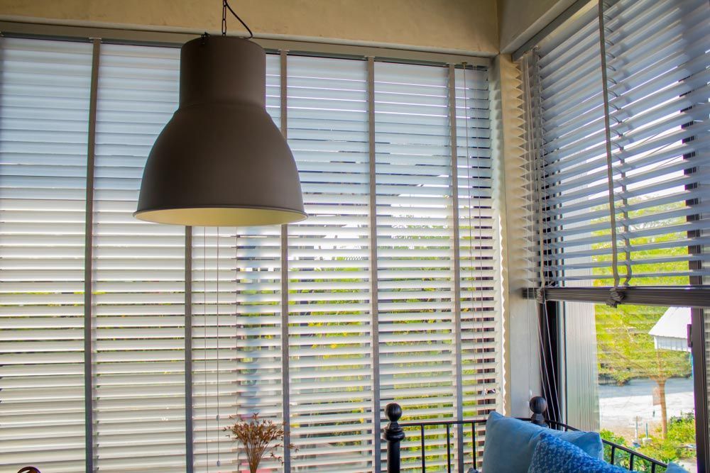 A Living Room With Lamp and Blinds on the Windows — TT Shutters & Shading In Tweed Heads, NSW