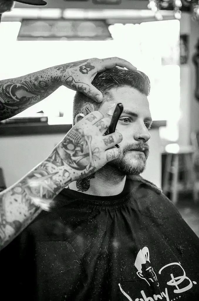 A Man Is Getting His Hair Cut By A Barber In A Black And White Photo — The Barber Social In Raymond Terrace, NSW