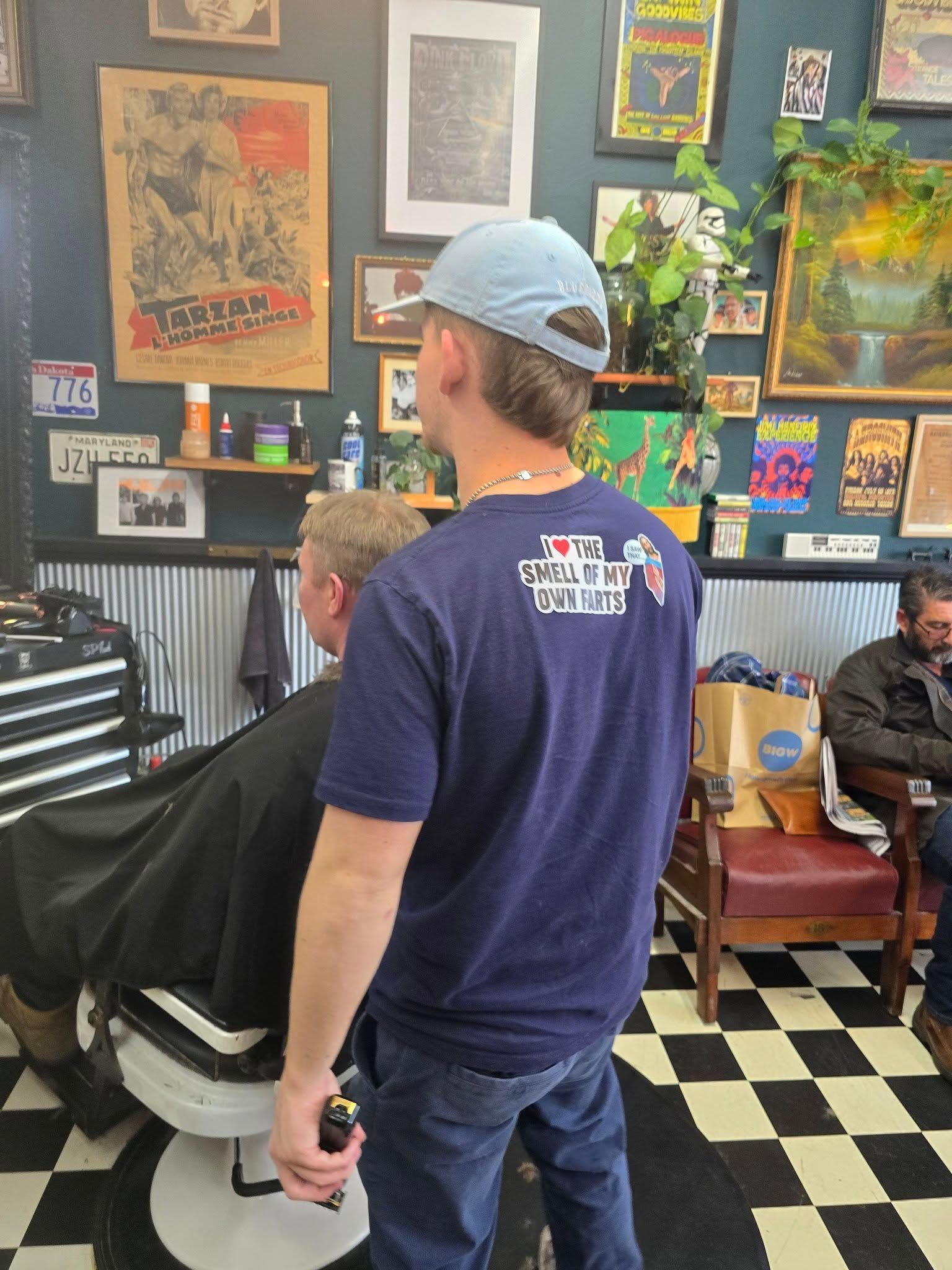 A Barber Wearing a Blue Cap Cuts a Client's Hair in A Barbershop — The Barber Social In Raymond Terrace, NSW