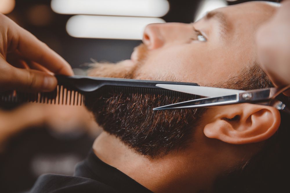 A Barber Uses a Comb and Scissors to Trim a Man Beard in A Close Up Shot — The Barber Social In Raymond Terrace, NSW