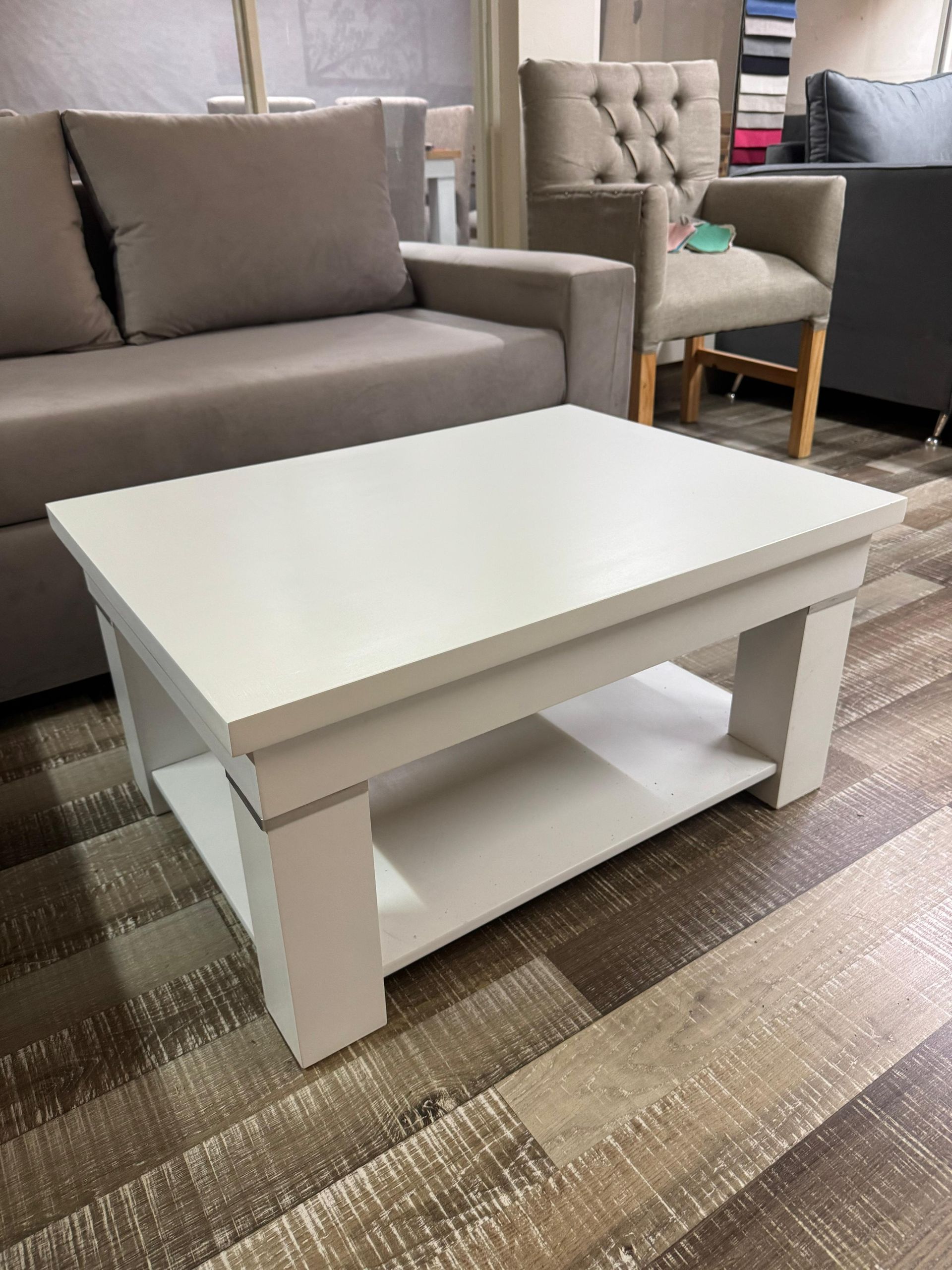 Una mesa de centro rectangular blanca con un estante inferior