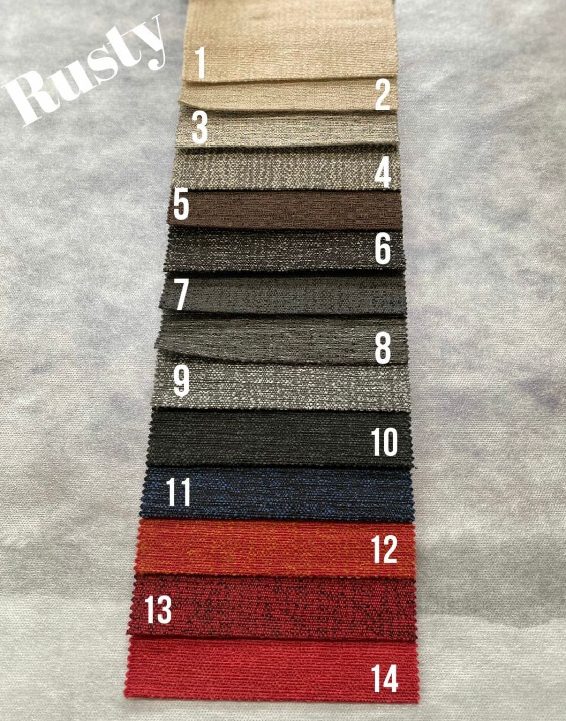 Un sofá de tela gris con dos grandes cojines en el respaldo se encuentra sobre un suelo con estampado de madera