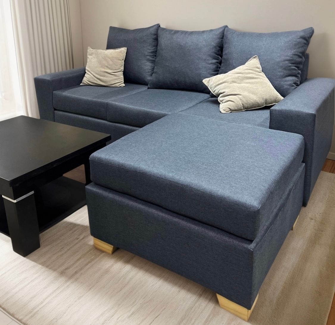 Un sofá modular azul con dos cojines decorativos de color beige