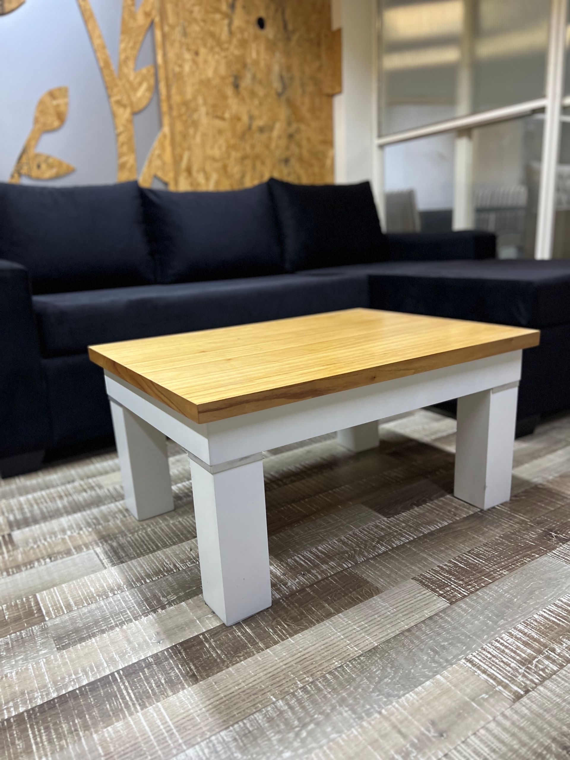 Una mesa de centro con tablero de madera clara y patas blancas