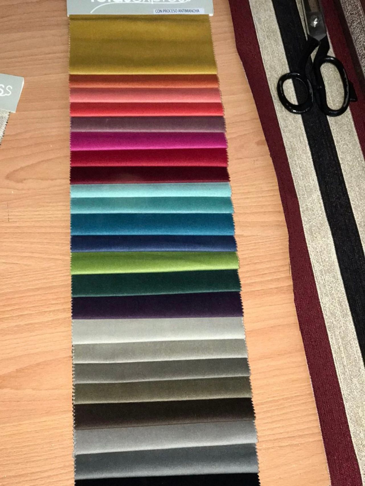 Una silla de comedor de madera clara con asiento tapizado en gris se encuentra en un comedor con una mesa y sillas a juego.