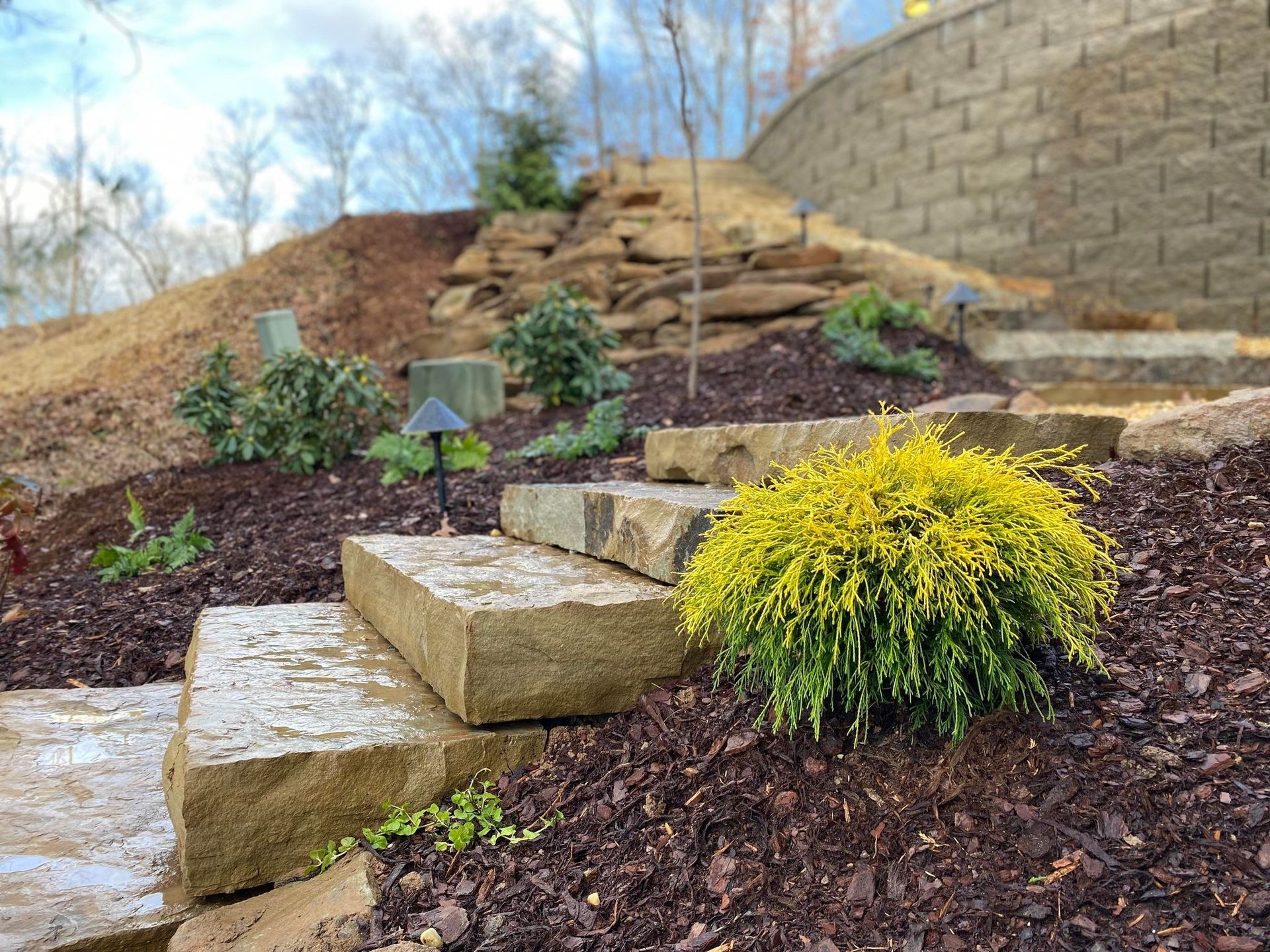 A stone staircase leading up to a hill with a brick wall in the background