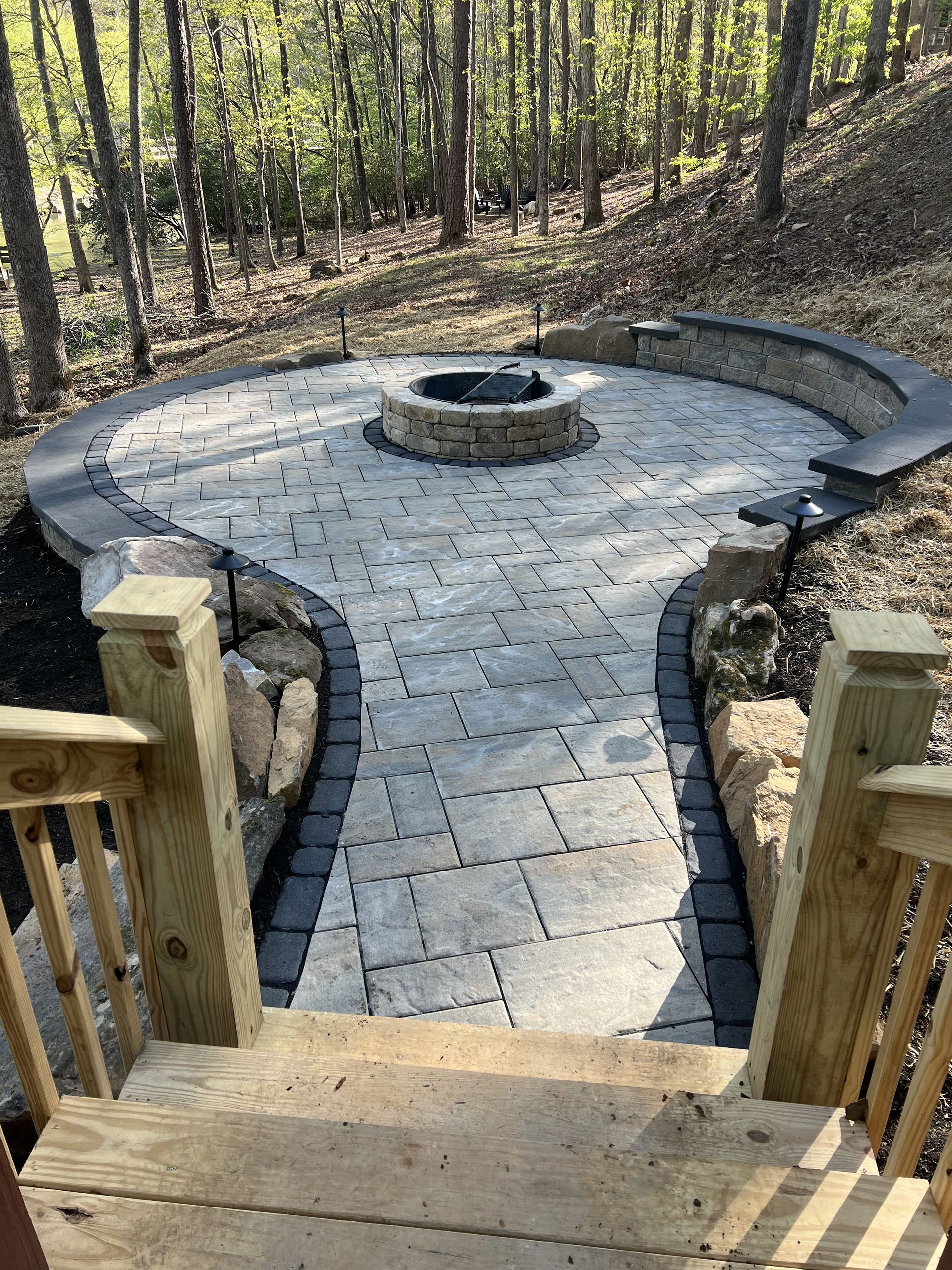 A stone walkway leading to a fire pit in the middle of a forest.