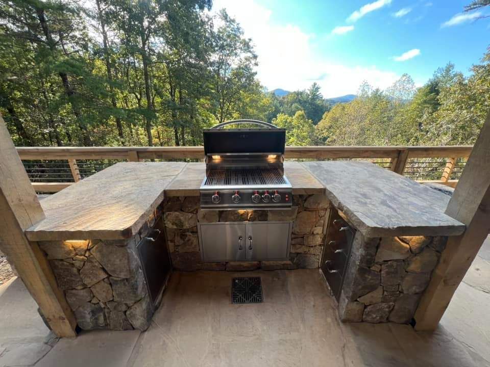 An outdoor kitchen with a grill and trees in the background