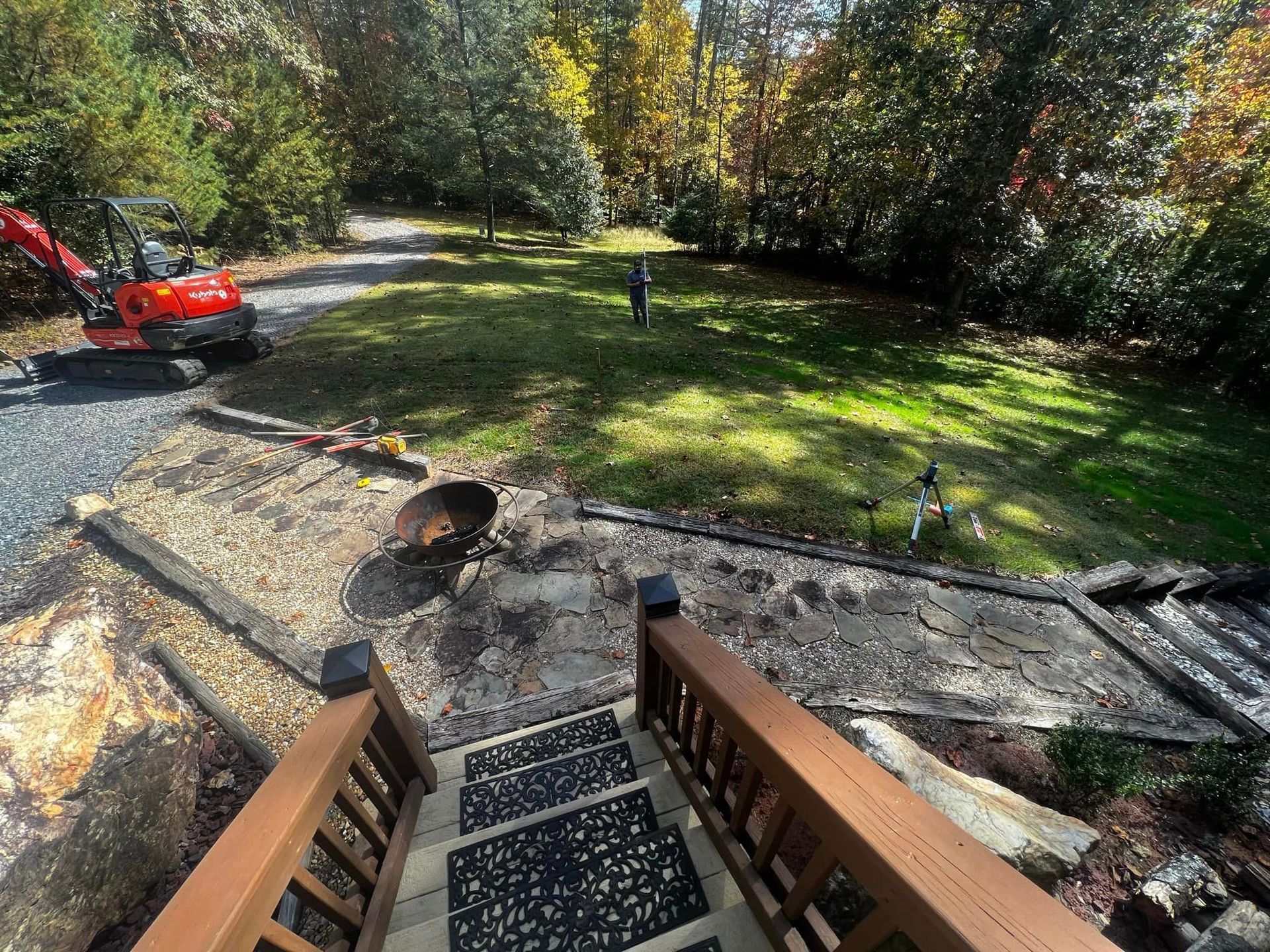 A wooden deck with stairs leading up to a lush green yard.