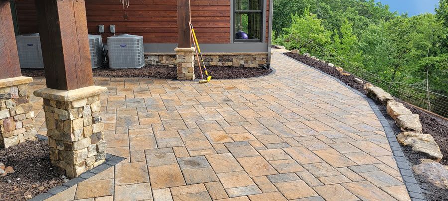 Stone patio next to a house with a wooded view.