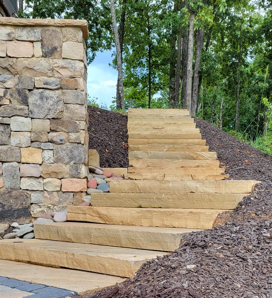 Stone steps lead uphill alongside a stone pillar, set in a natural landscape.