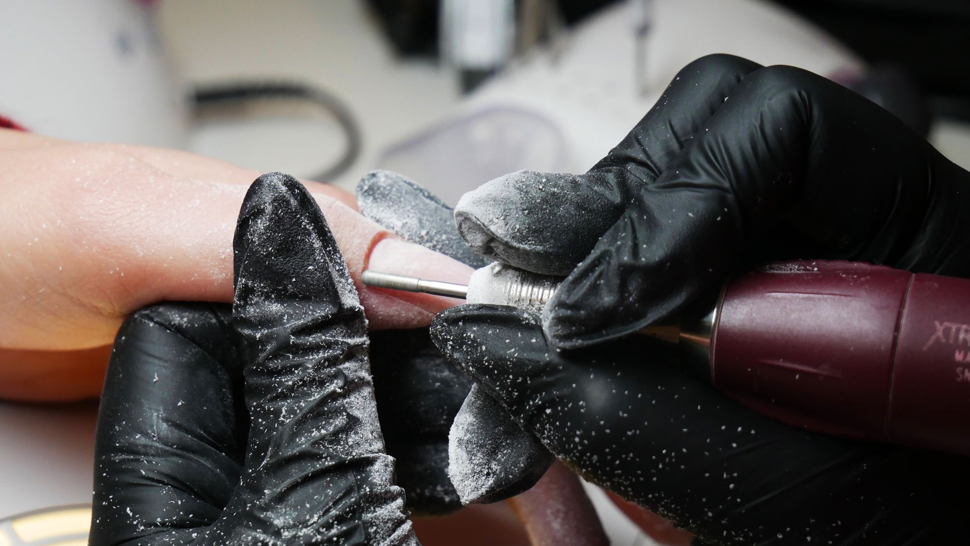 un primo piano di una persona che fa un manicure a una donna con guanti neri .