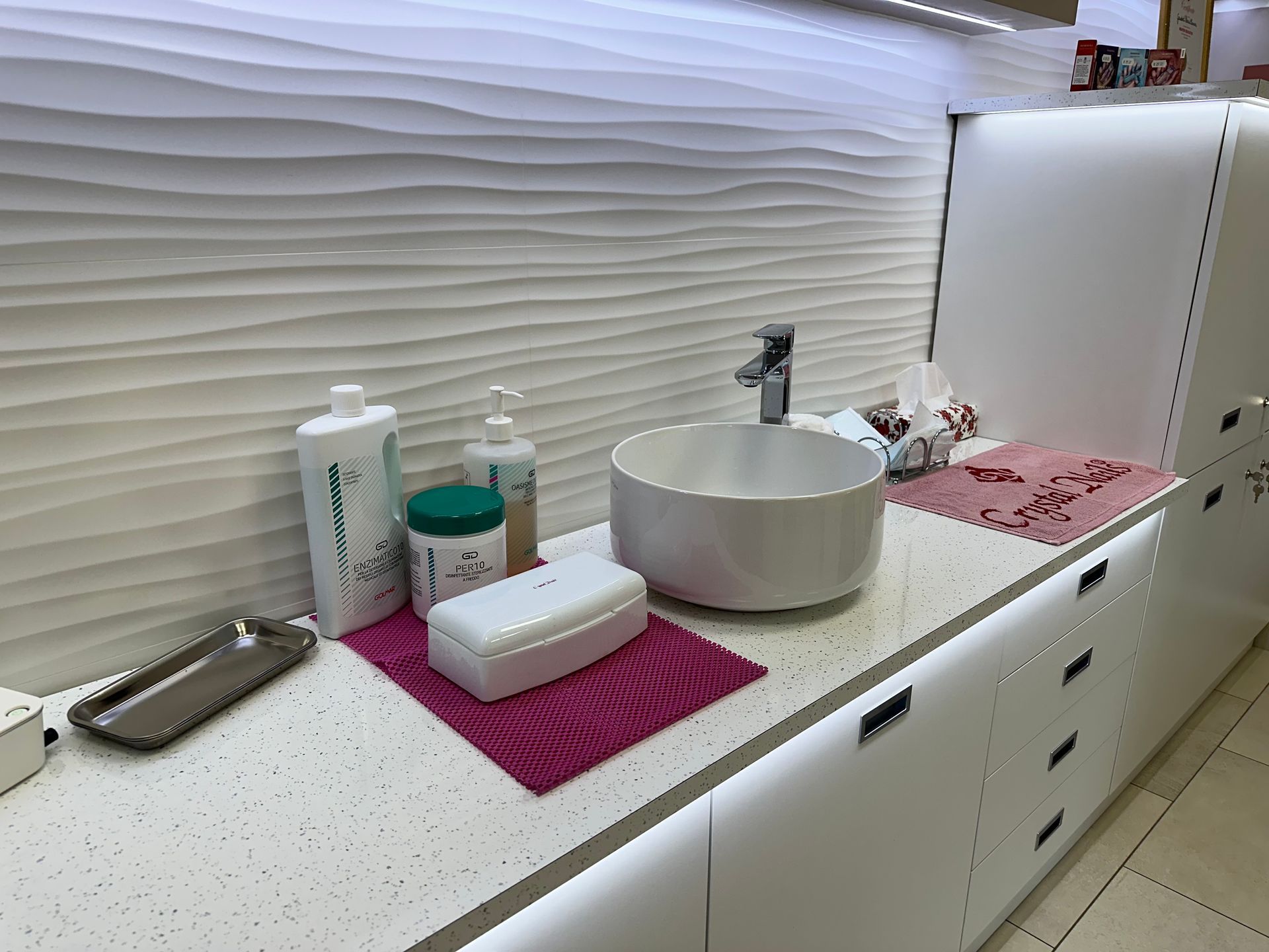 una stanza da bagno con lavabo , asciugamani , bottiglie e altri prodotti .