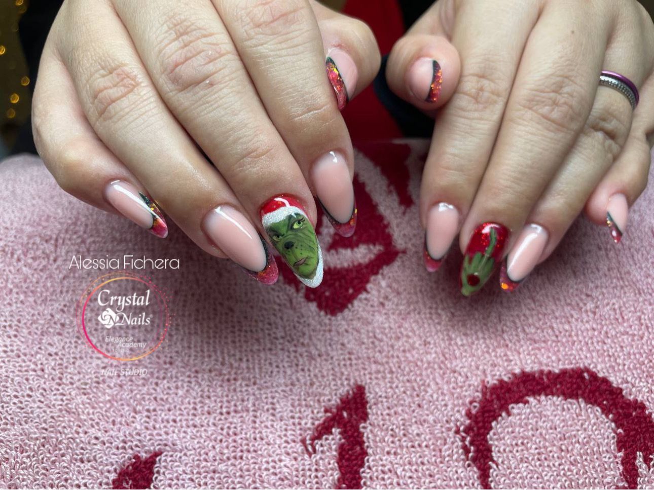 una donna tiene in mano un asciugamano rosa con le unghie decorate per natale .