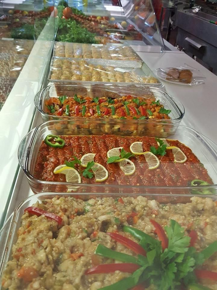 Vetrina con vari cibi preparati, tra cui insalate e piatti con verdure ed erbe aromatiche.