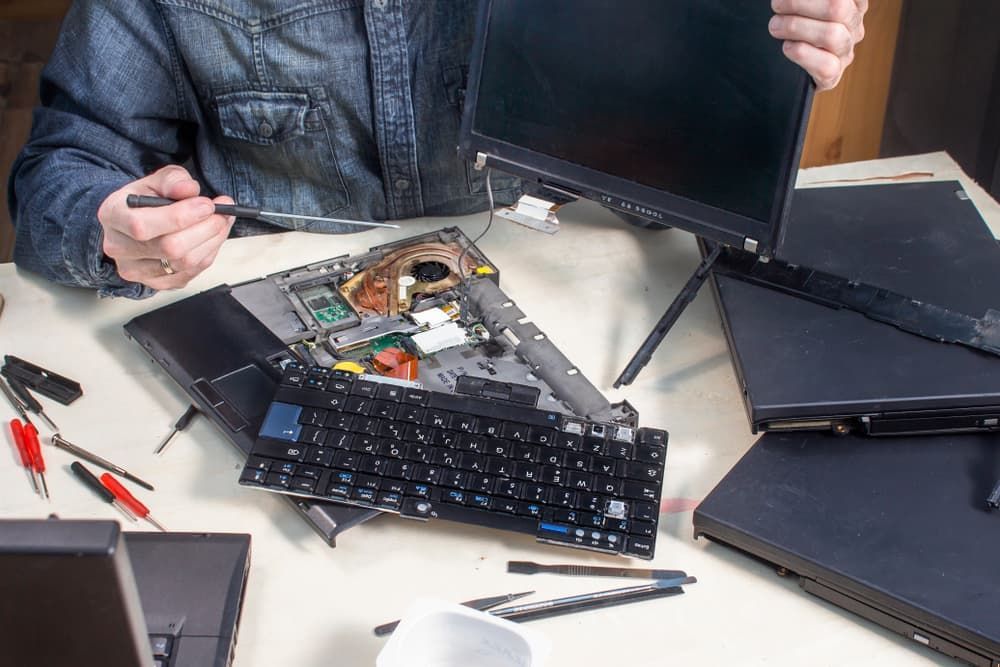 A Man is Fixing a Laptop Computer With a Screwdriver — Leading Edge Computers in Forster, NSW