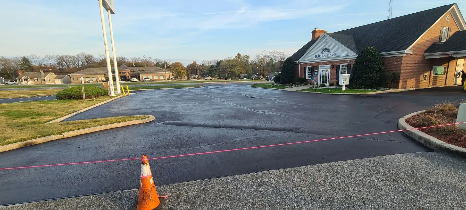 Exterior view of a building with a parking lot; traffic cone and pink line on the asphalt.