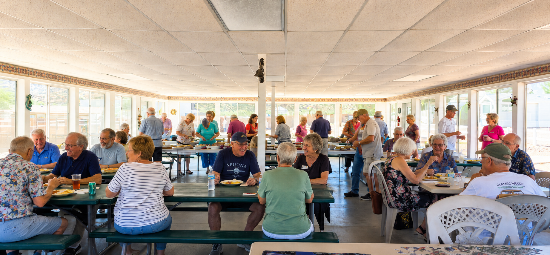 People seated at picnic tables in a bright open-air pavilion, eating and socializing.