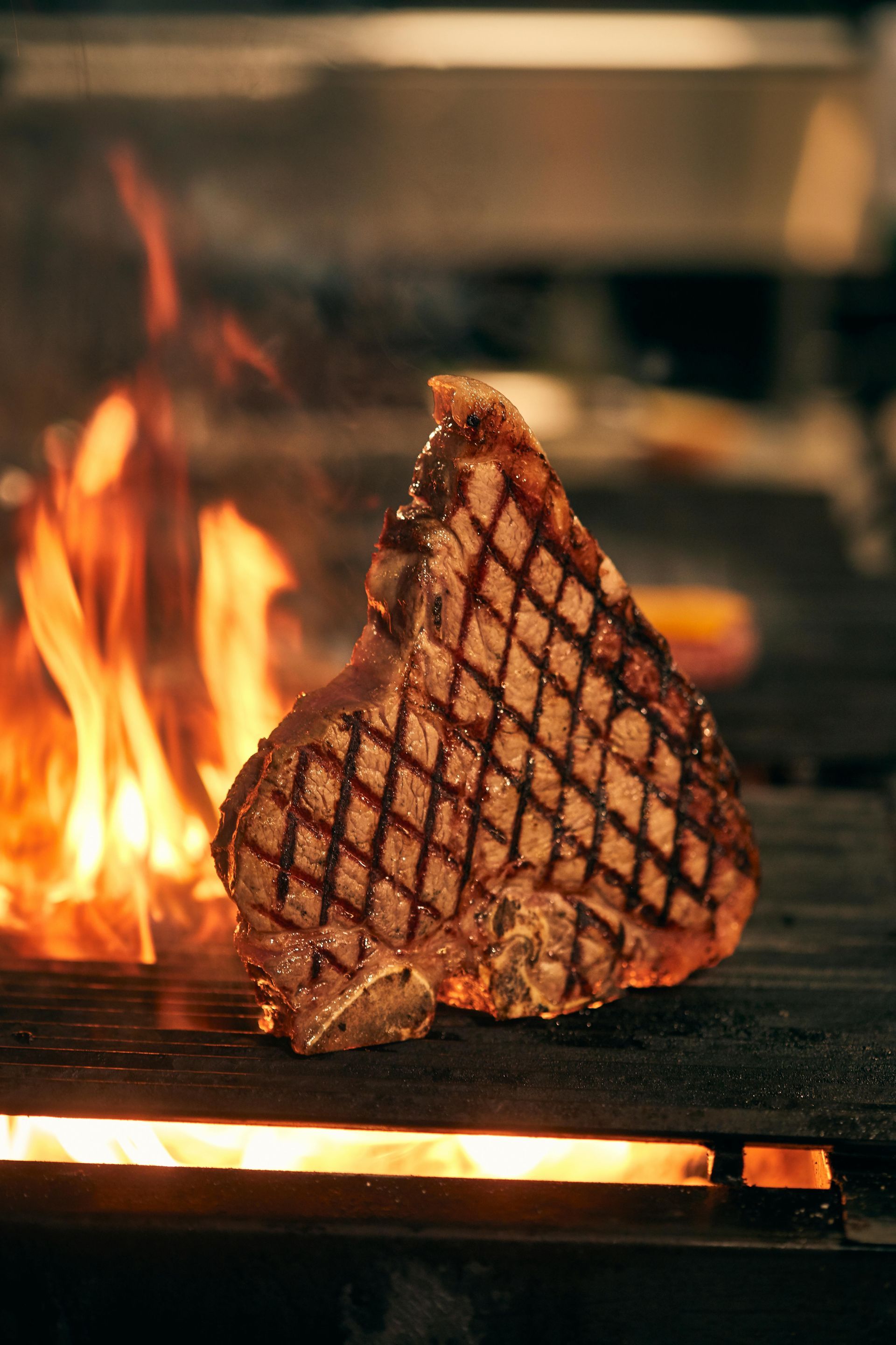 Grilled steak with crosshatch marks over open flames on a barbecue grill