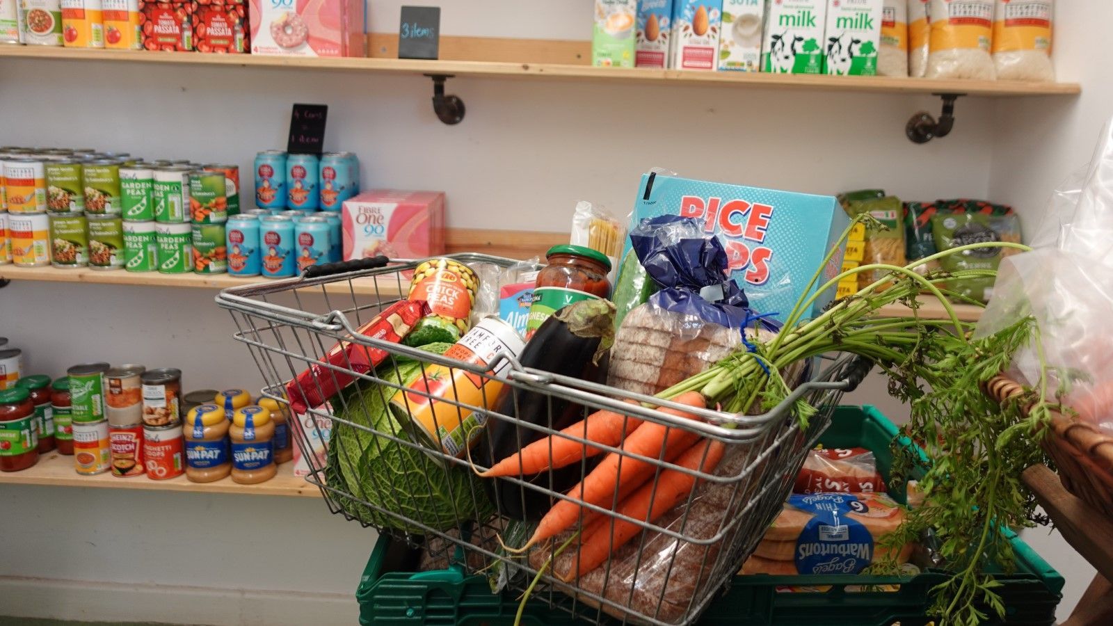 A shopping cart filled with carrots , cabbage , and other vegetables.