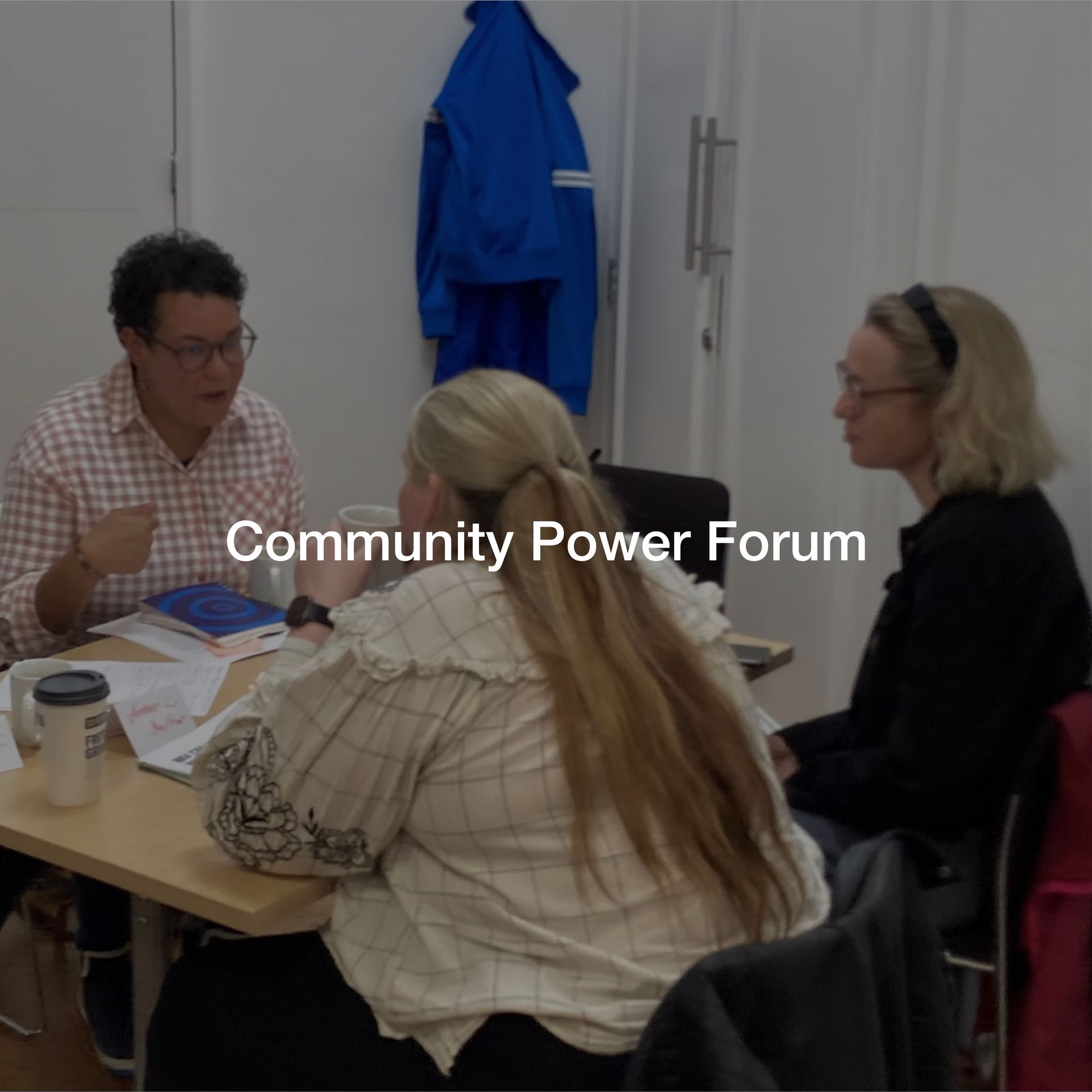 A group of people are sitting around a table with the words community power forum on the bottom
