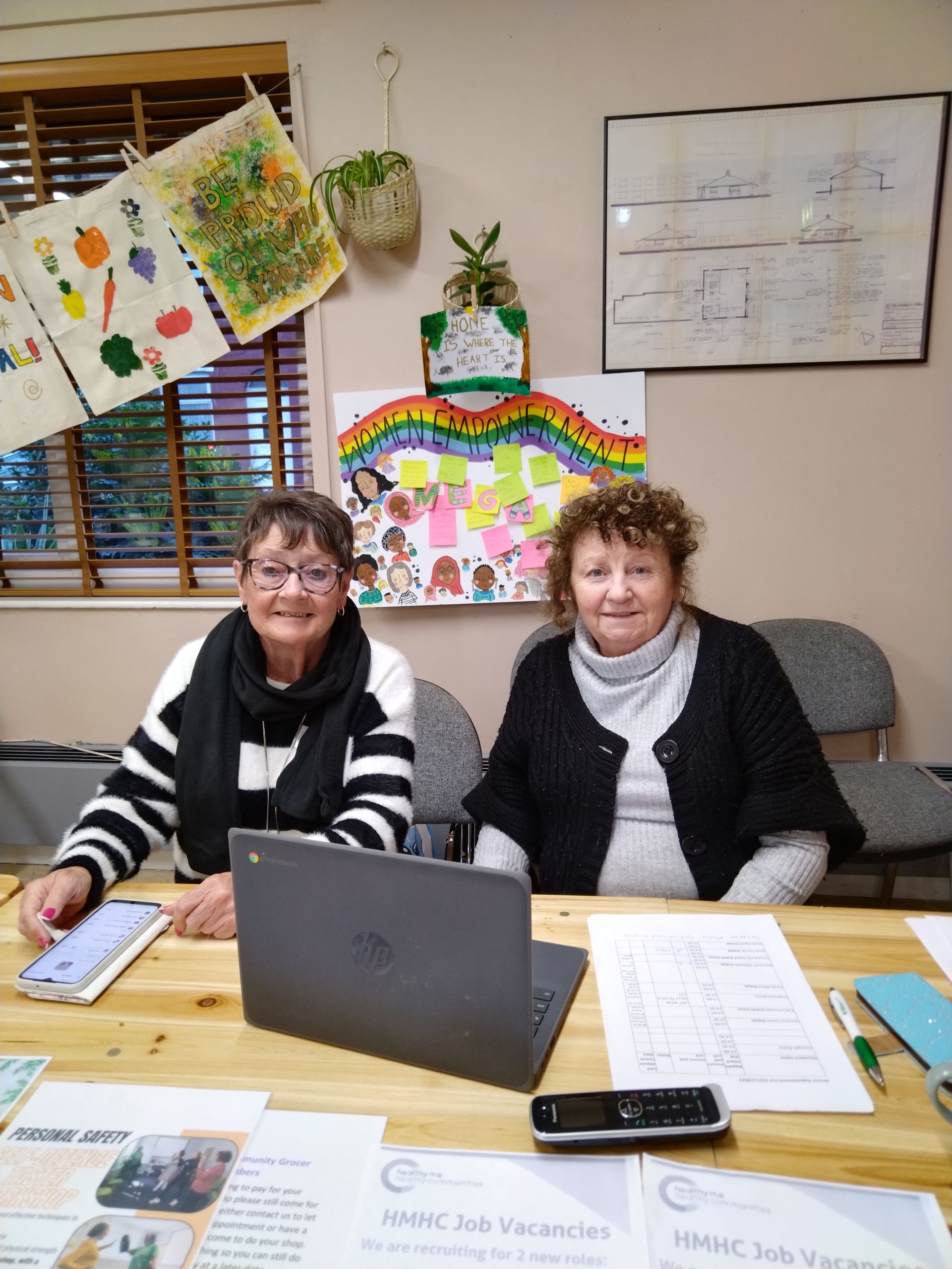 Two women are sitting at a table with a laptop.
