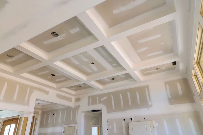 Vista interna di una stanza in costruzione, che mostra la struttura in legno delle pareti, i pannelli in cartongesso e le travi a vista del soffitto.