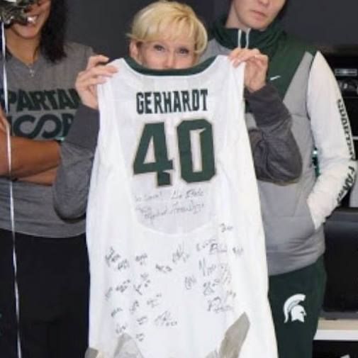 Person holds up a signed white football jersey labeled