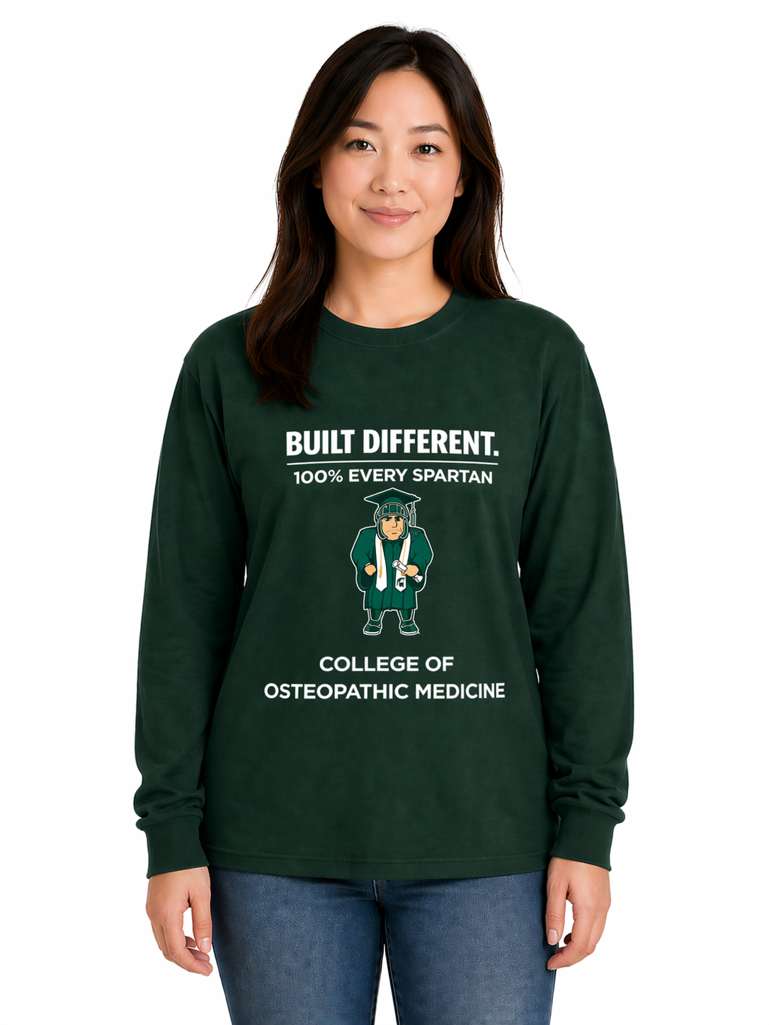 Woman in a dark green sweatshirt and jeans standing against a white background.