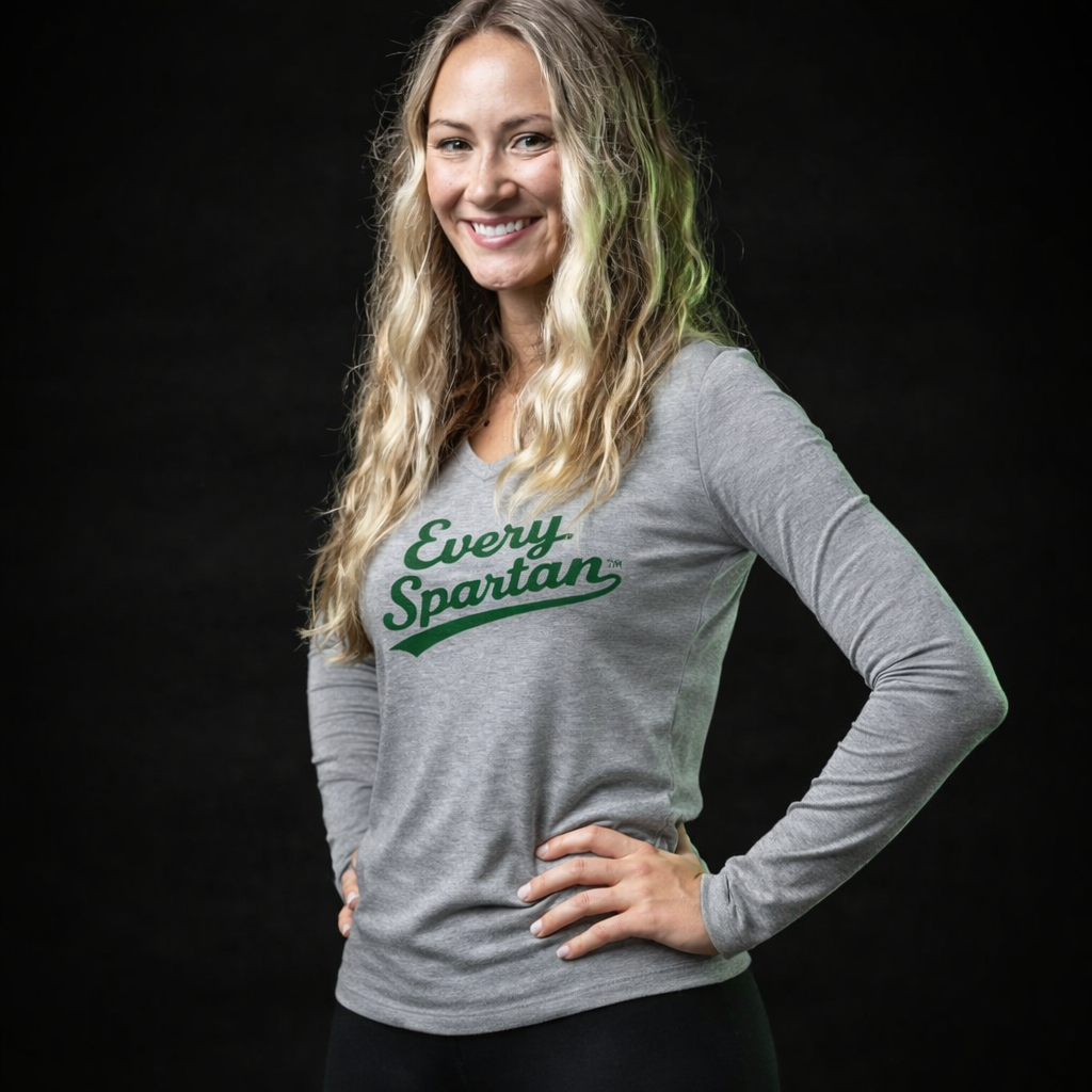 A smiling person wears a grey long-sleeved shirt with the green text 