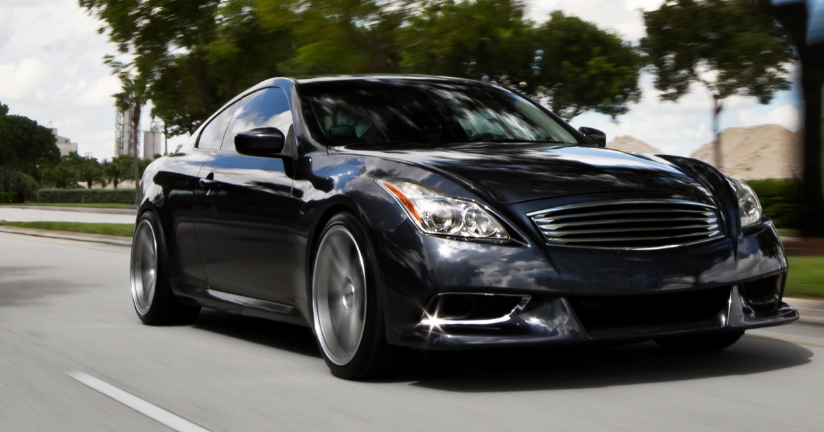 Black Infiniti coupe driving on a road.