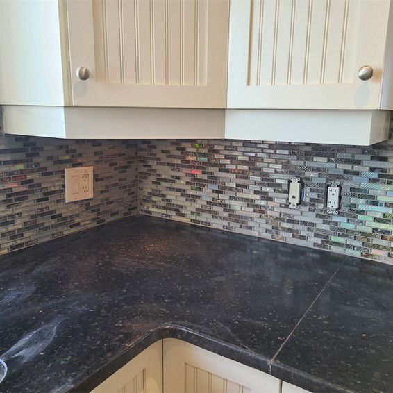 A kitchen with a black counter top and white cabinets