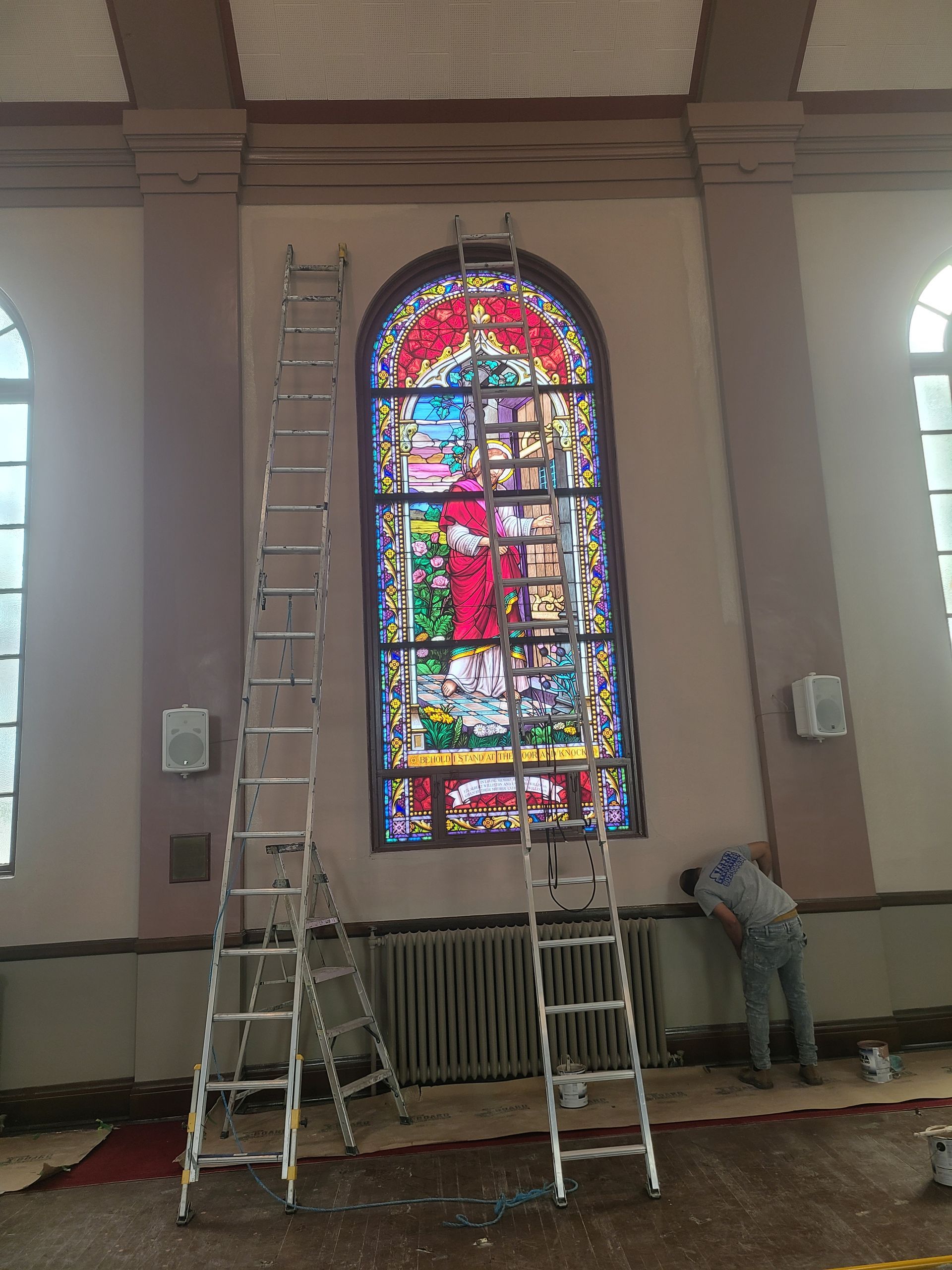 A man is painting a stained glass window in a church.