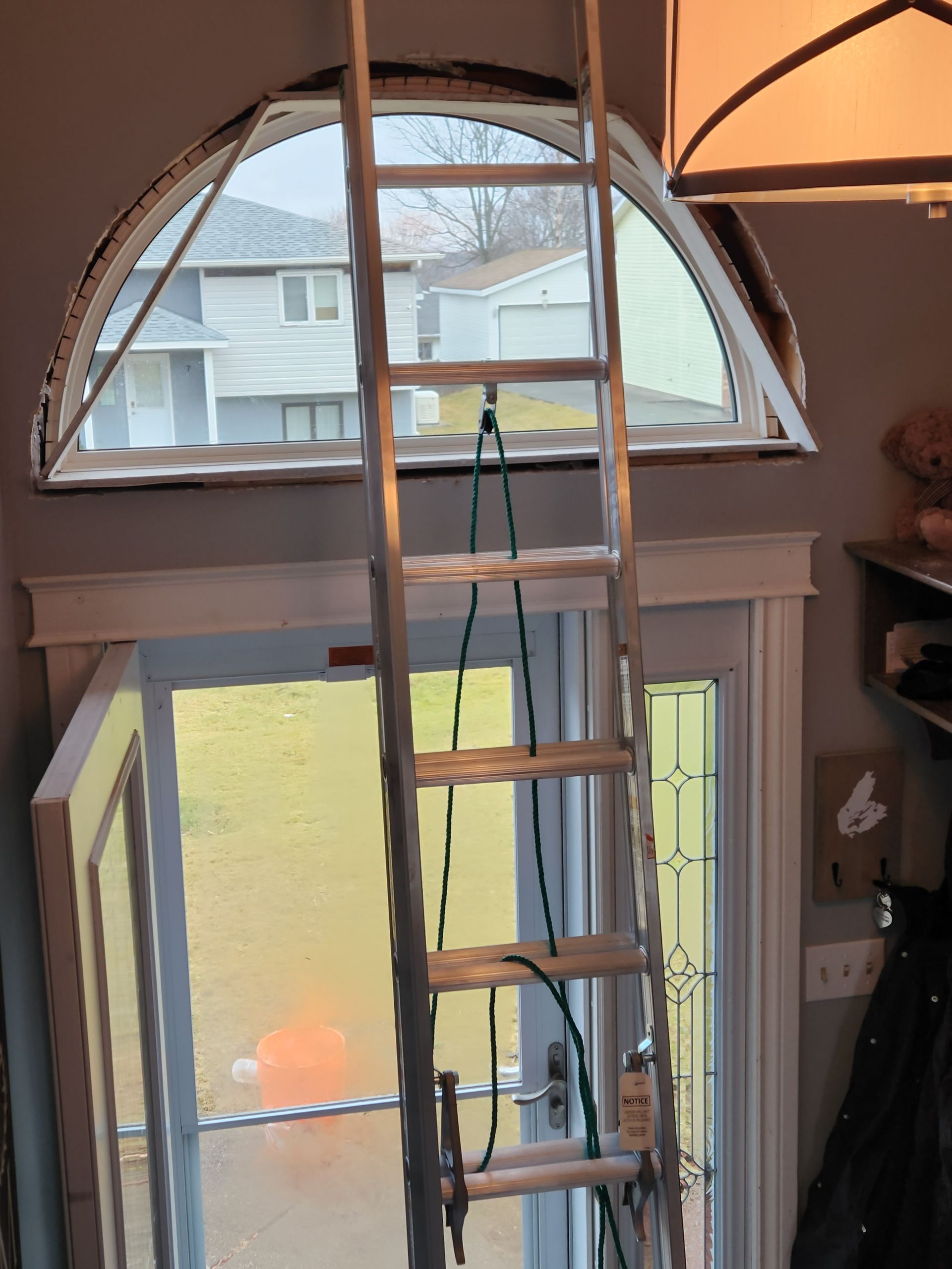 A ladder is hanging from the ceiling in front of a window.