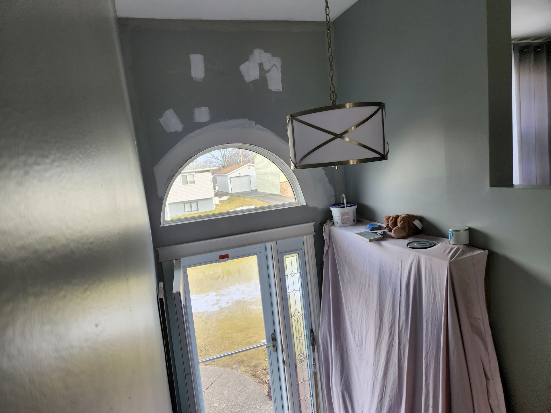 A room with a large window and a lamp hanging from the ceiling.
