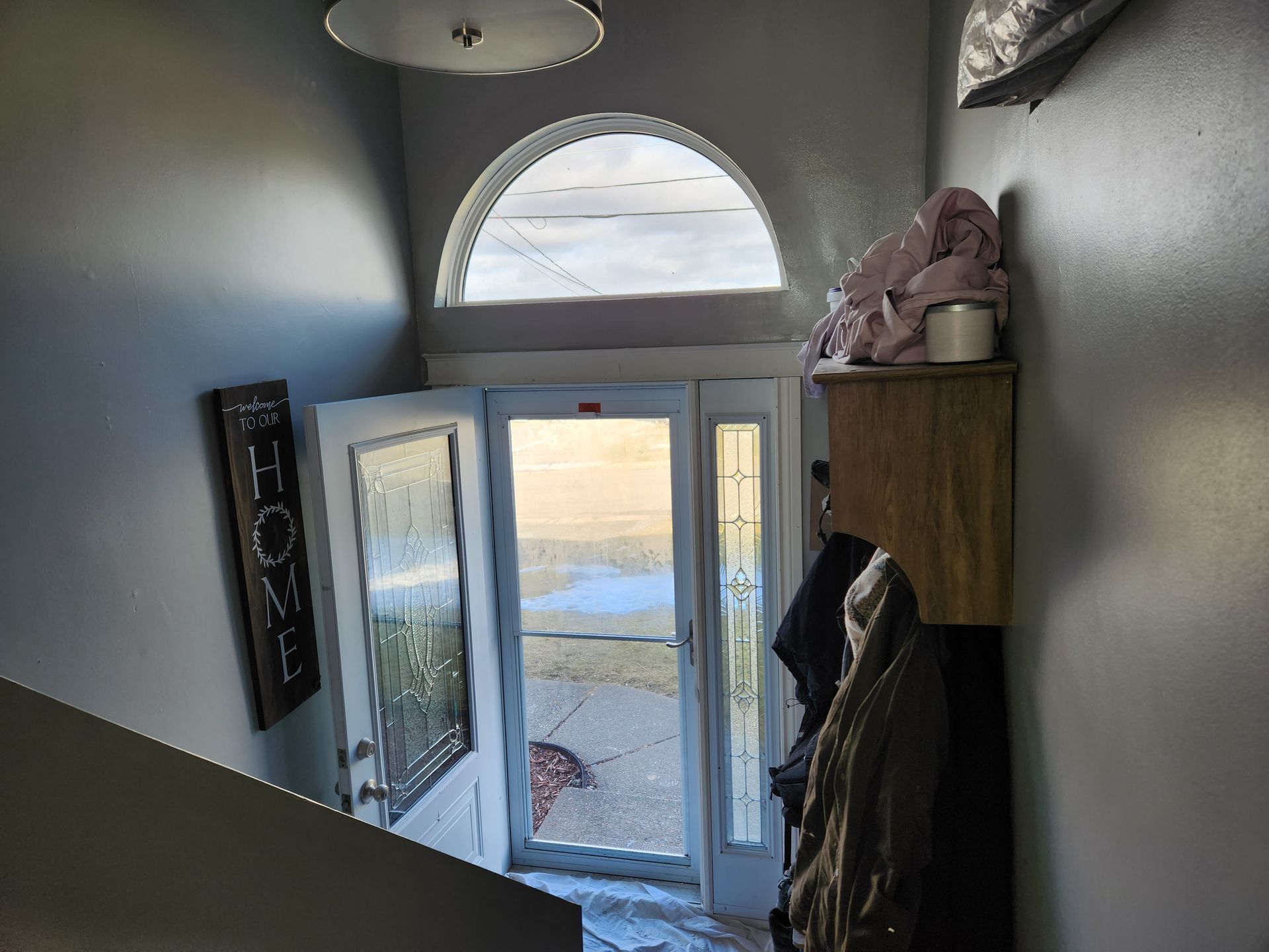 A hallway with a door open and a sign on the wall that says `` home ''.