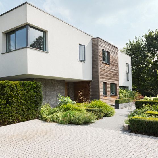 A modern house with a lot of windows and bushes in front of it